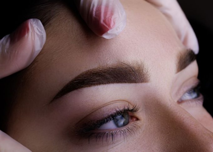 Kobieta sprawdza efekty po zabiegu makijażu permanentnego brwi