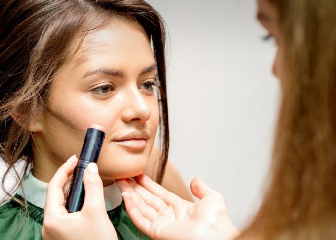 Kobieta u kosmetyczki wybiera bazę kolorystyczną pod makijaż